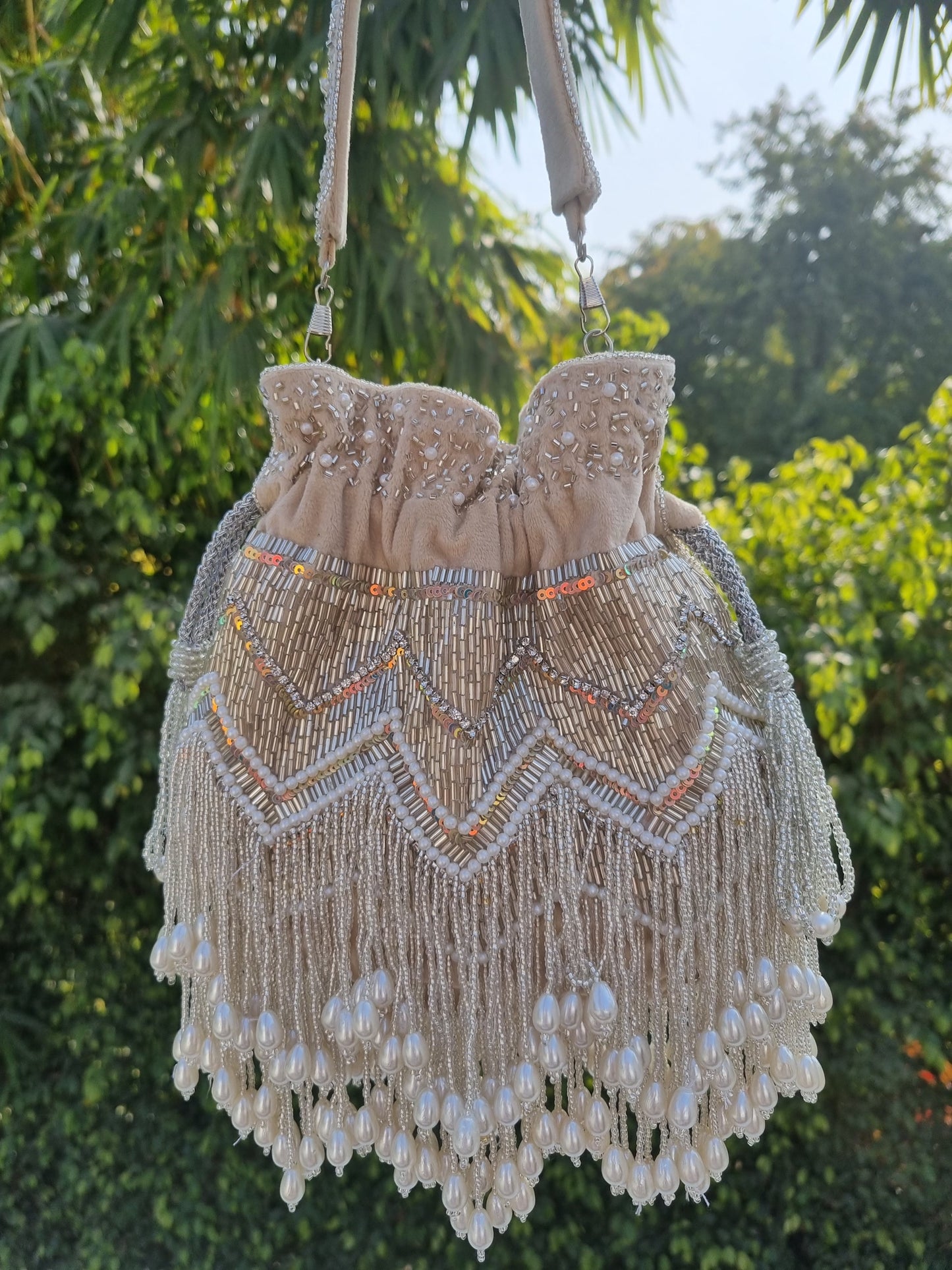 Beige pearl tassels Potli bag with intricate embroidery, traditional Indian clutch from aclutchstory featuring elegant design and tassel details.
