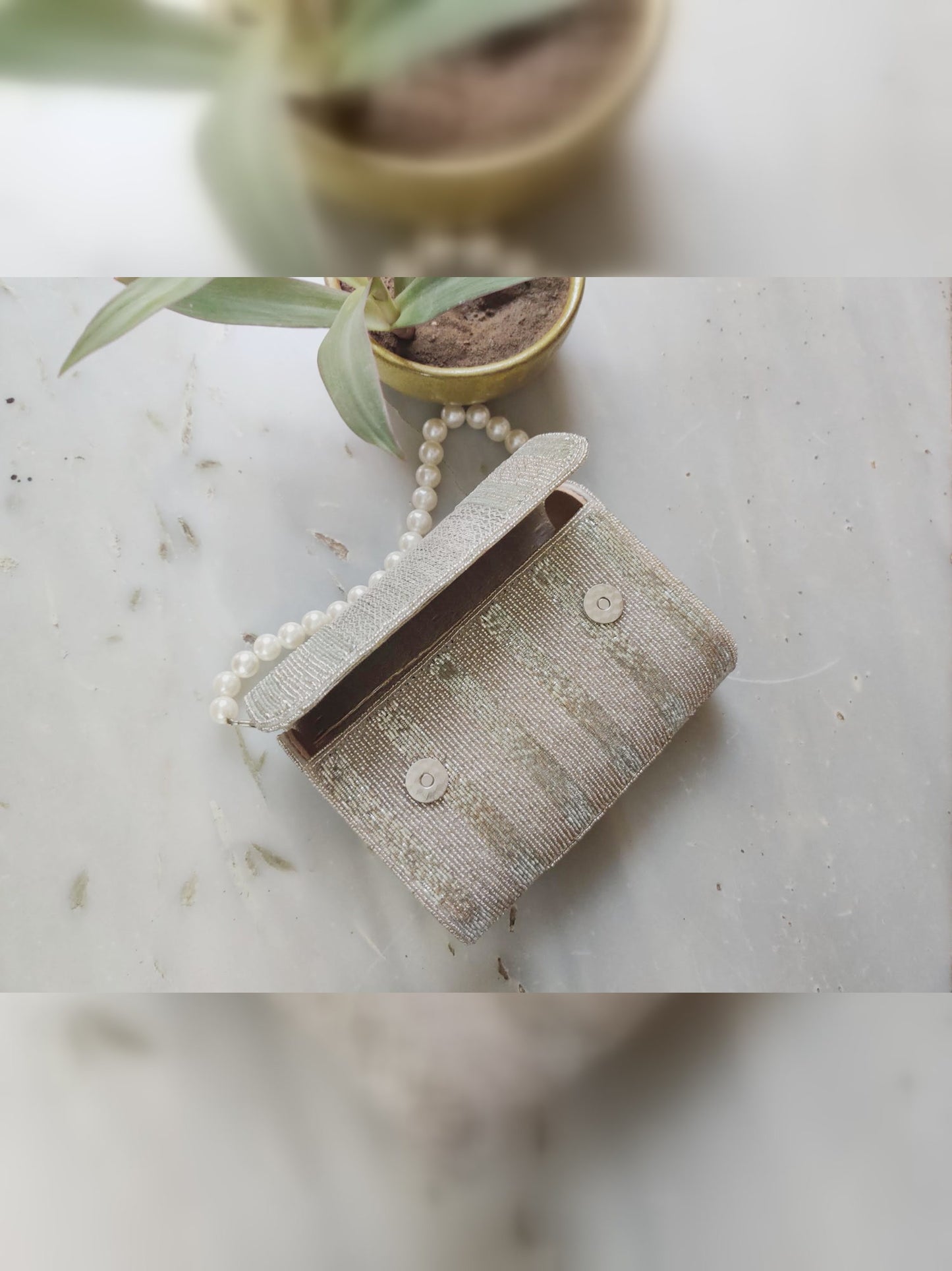 Silver beaded flapover clutch bag by aclutchstory featuring a sleek design and beaded detailing on the flap.