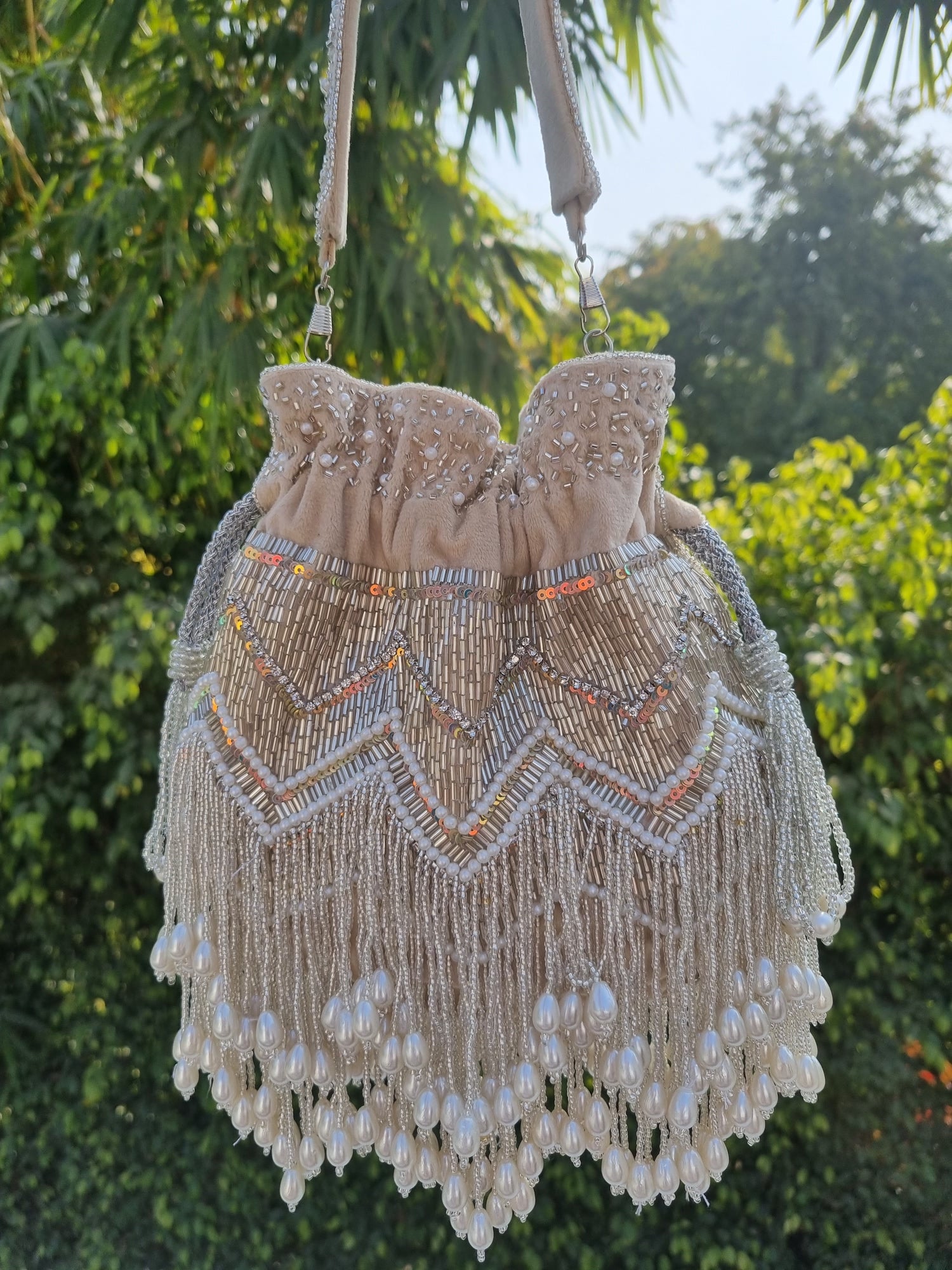 Beige pearl tassels Potli bag with intricate embroidery, traditional Indian clutch from aclutchstory featuring elegant design and tassel details.