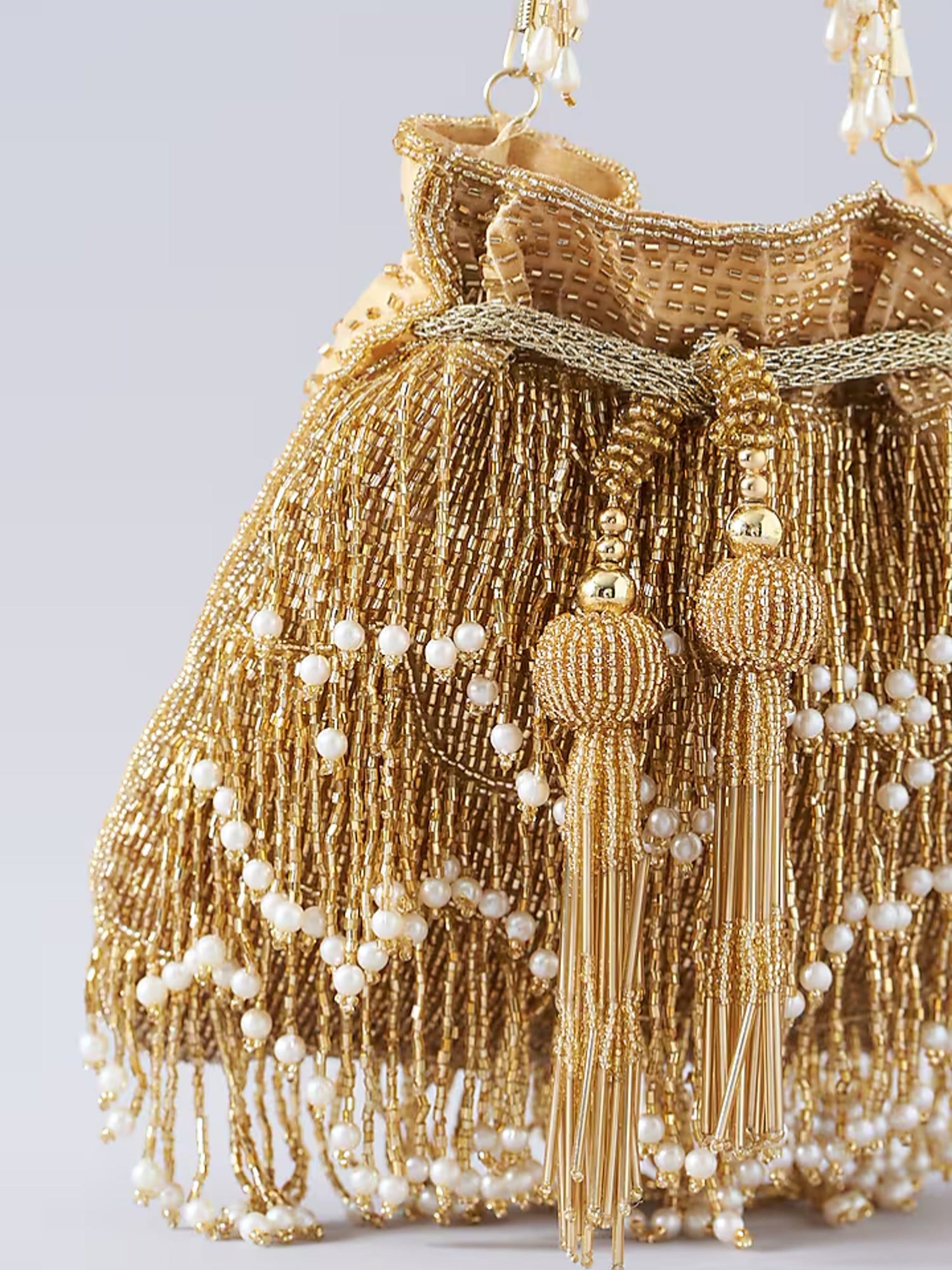 Gold fringe glam potli bag by aclutchstory featuring intricate embroidery and a drawstring closure, perfect for festive occasions.
