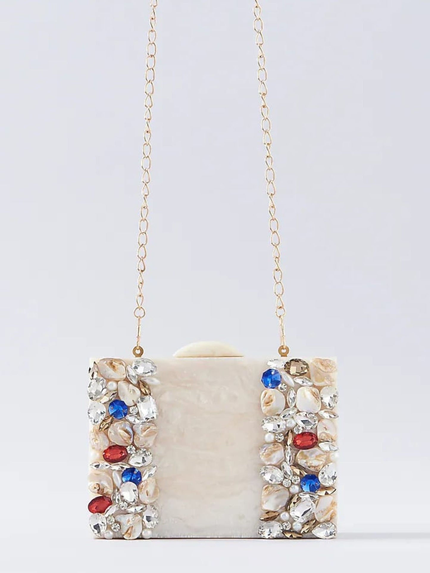 Ivory embellished resin clutch bag with intricate details, featuring a sleek rectangular shape and decorative accents.