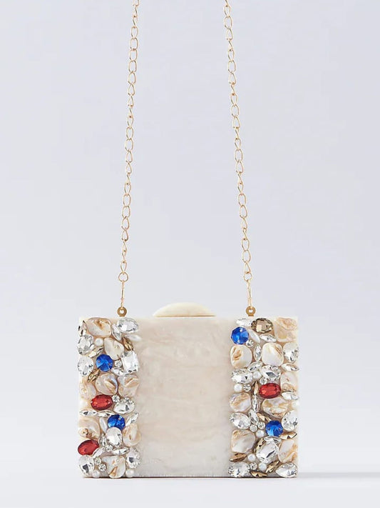 Ivory embellished resin clutch bag with intricate details, featuring a sleek rectangular shape and decorative accents.