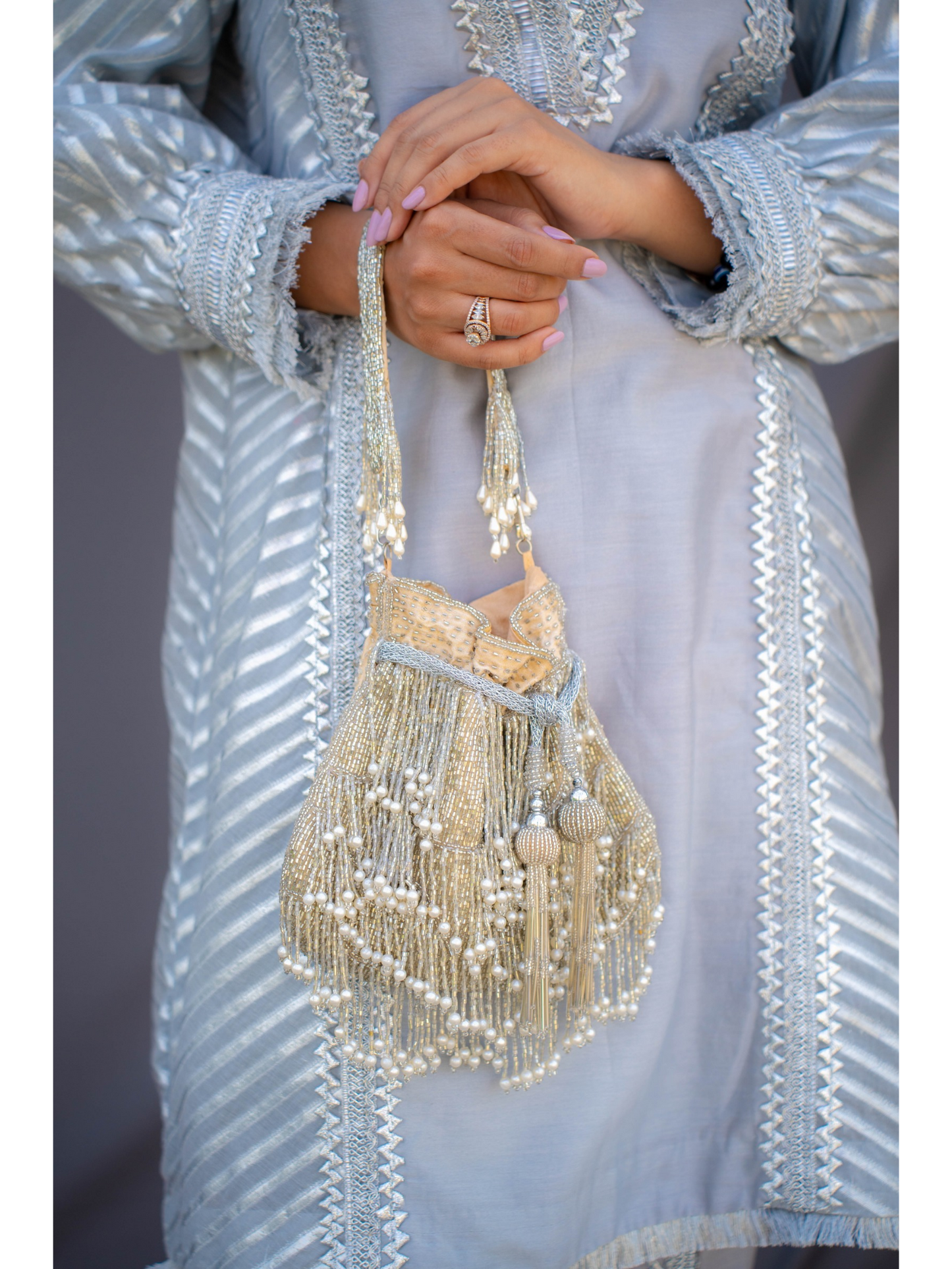 Silver fringe glam potli bag with white base and decorative embellishments, stylish accessory for traditional or festive occasions.